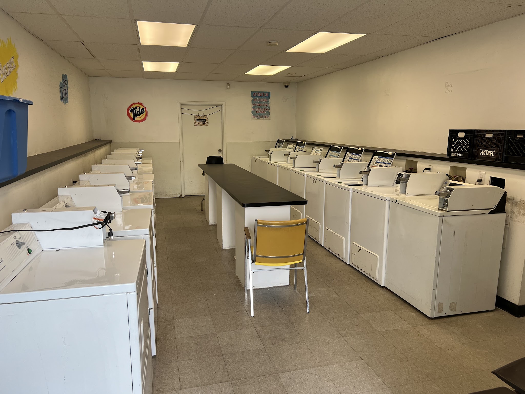 Self-serve laundry room with rows of coin-operated washers and dryers